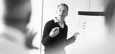 A man holds up a graph in front of a group of people at a seminar