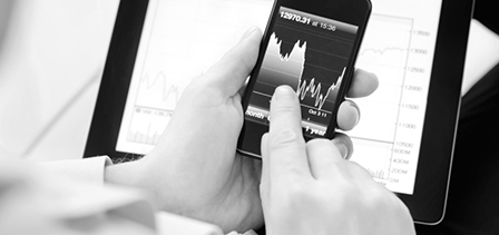 A man points at a graph of the stock market on his mobile device