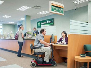 Photo d'un client en fauteuil roulant motorisé au comptoir d'une succursale